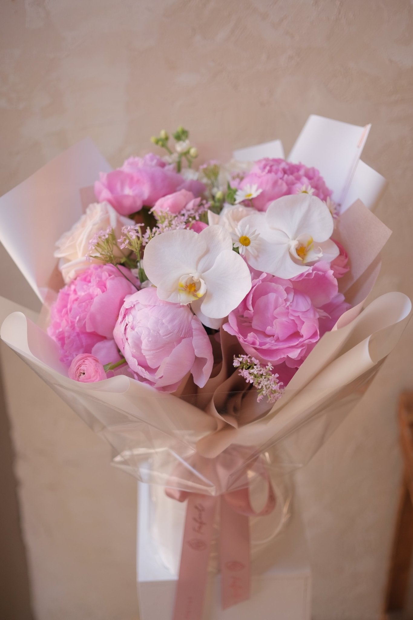 Light pink peony and white orchid bouquet with peach rose, front shot by Faful Florist